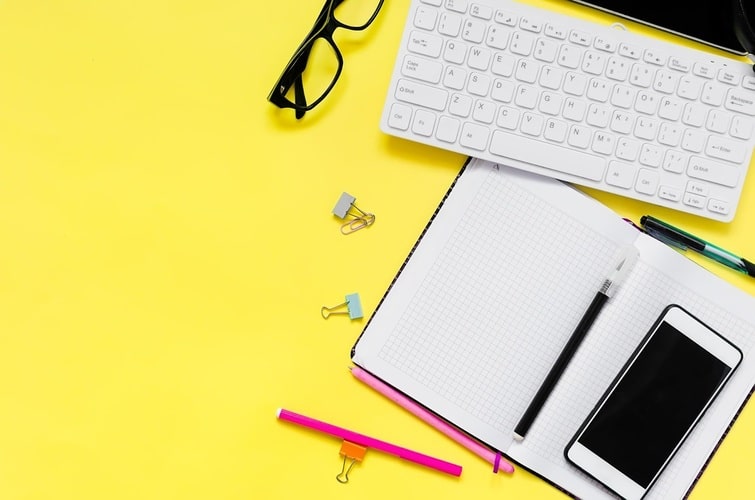 Picture of a desk with a kayboard and a notepad